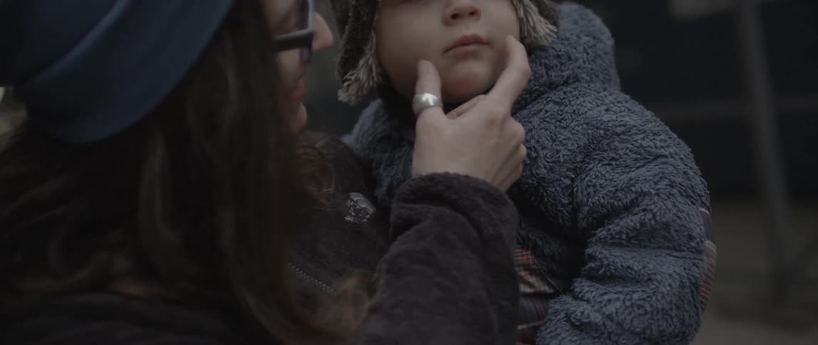 A woman touches a child's face in her arms