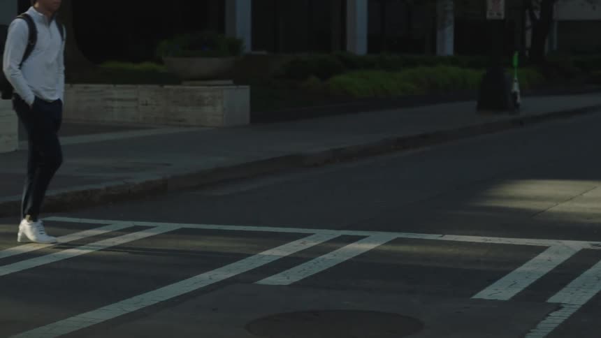 Man with a backpack crossing an empty street at the crosswalk