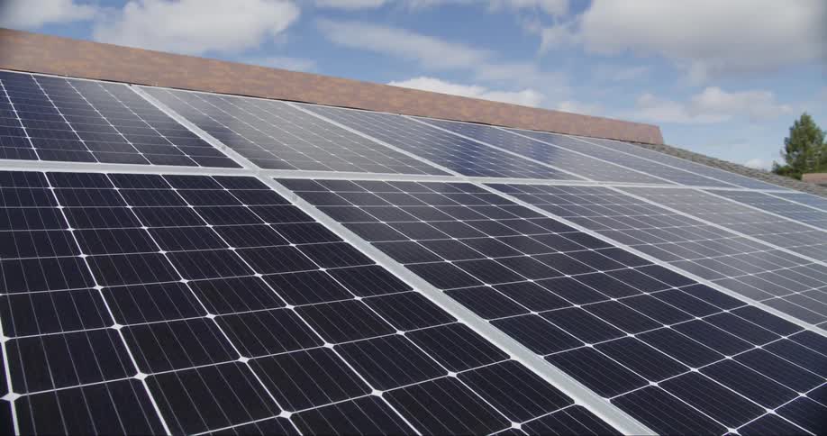 Passing clouds reflect on solar panels on a building