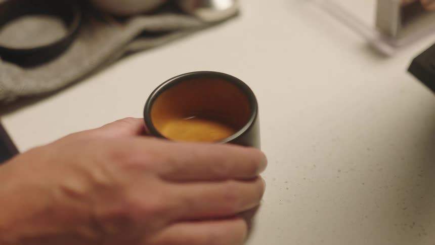 A person hand spinning a small cup of cappuccino