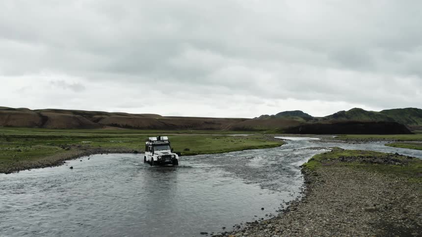 A truck is driving off road in the stream