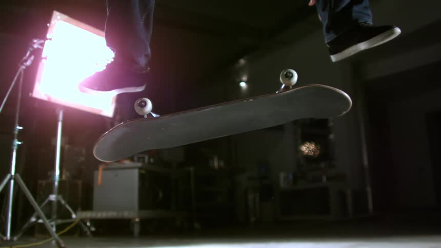 Closeup of a mans feet jumping in a skateboard trick inside a studio