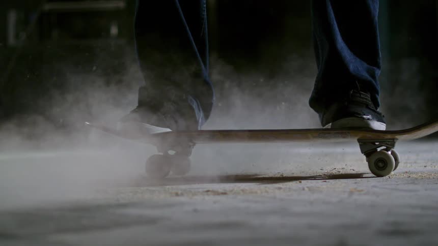 Close up of a skateboard sliding and kicking dust