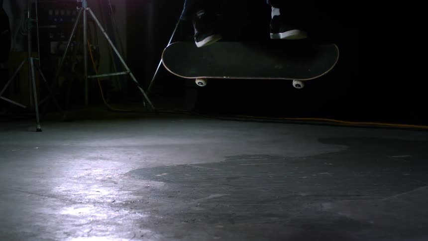 Closeup of a mans legs jumping in a skateboard trick inside a studio