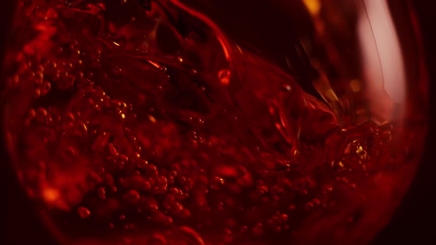 Close up of red wine pouring inside a glass goblet