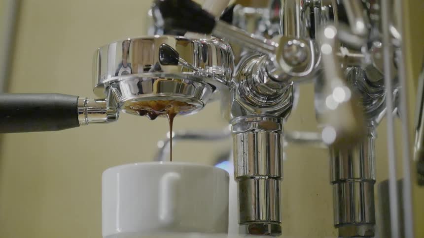 Coffee pours from a nozzle into a mug