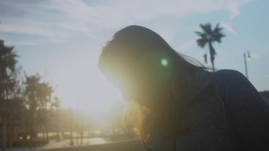A woman is standing on the street at sunset