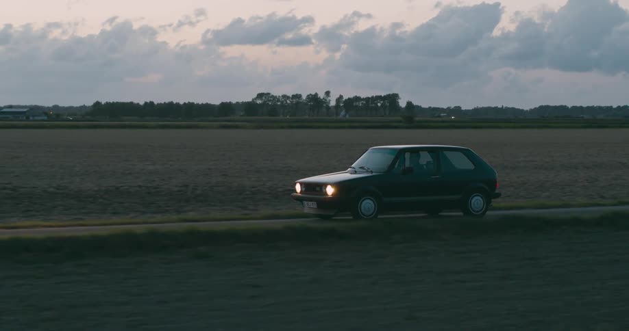 An old car driving along a deserted road in the rural landscape
