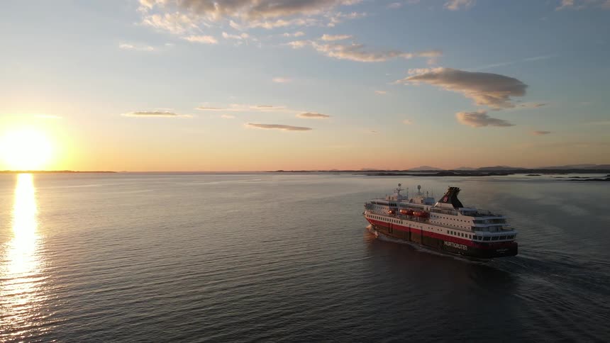 Cruise ship sailing through the calm sea near the coast during a beautiful sunset