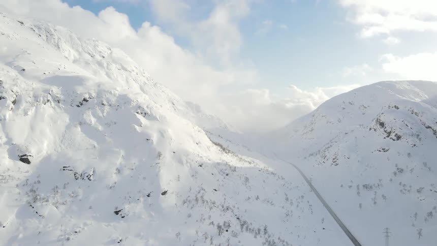 Aerial of a frozen mountain with a deserted road during the day
