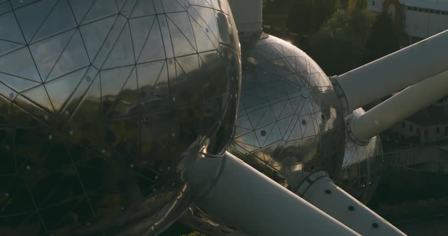 Metal globes with protrusions possible a satellite rotates above a landscape of trees and buildings