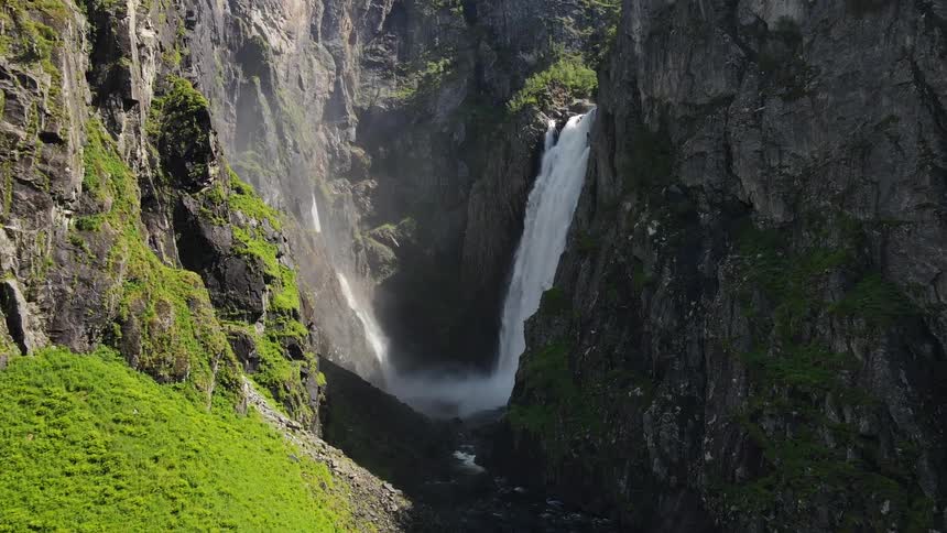 A waterfall in a valley in the middle of rocky mountains
