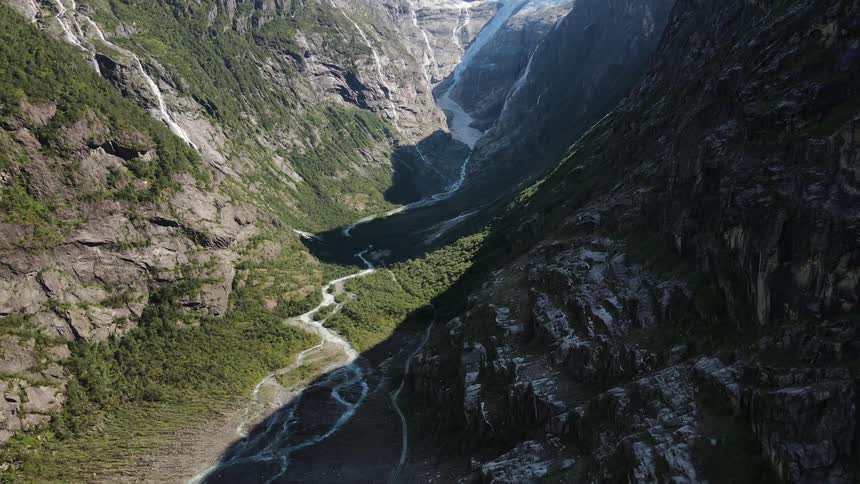 Aerial of a valley with mountains and stream during a sunny day