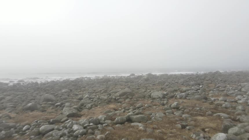 Landscape of a rocky shore facing the sea on a cloudy and hazy day