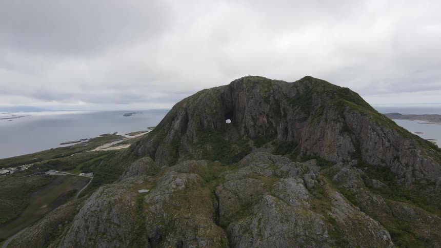Aerial of an island with a rocky mountain on a cloudy day