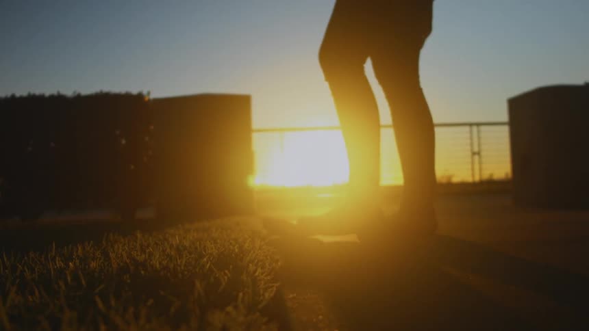 A woman walks outside at sunset