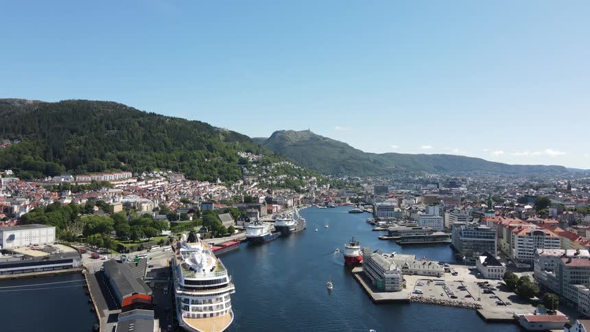 View of a cruise ship docked in the middle of a peninsula with a city