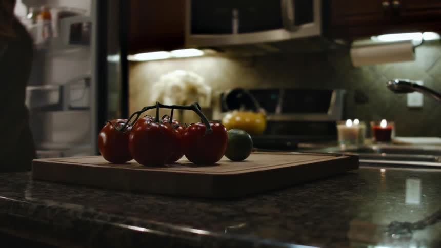 A woman puts some vegetables on a cutting board