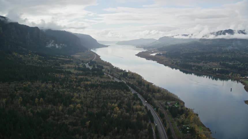 Aerial of a road on the banks of a river surrounded by forest