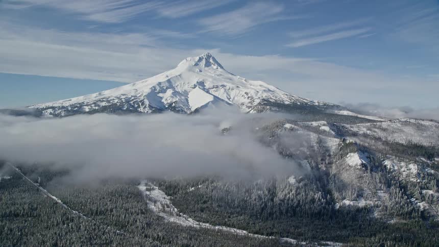 An aerial view of a huge mountain with a snowcapped peak