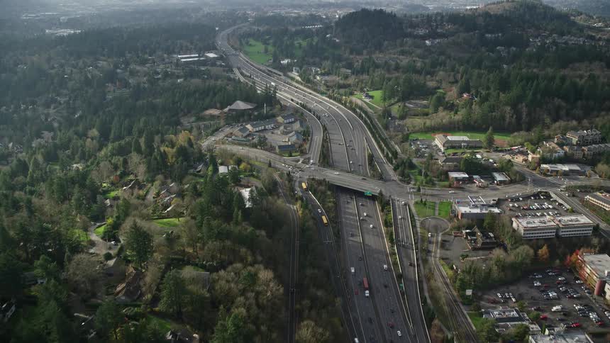 Cars drive on the highway past some buildings