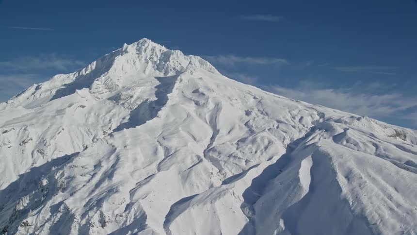 Mountain covered in snow under a blue sky with few clouds