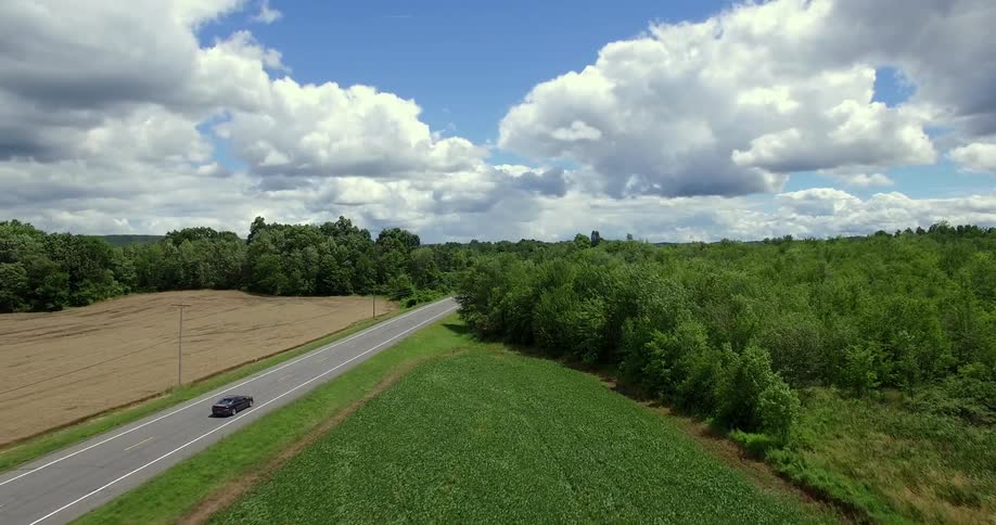 A black car is driving down the road ahead