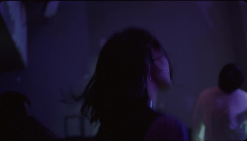 Woman walking towards a nightclub entering and dancing energetically with her back to the viewer