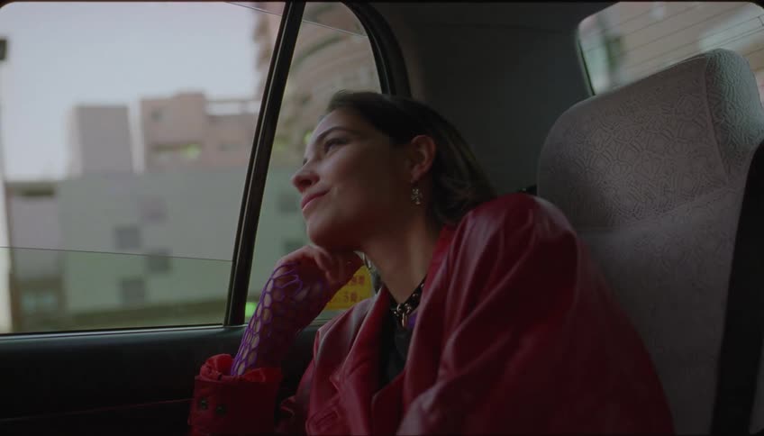 A lady smiling inside a moving car at midday