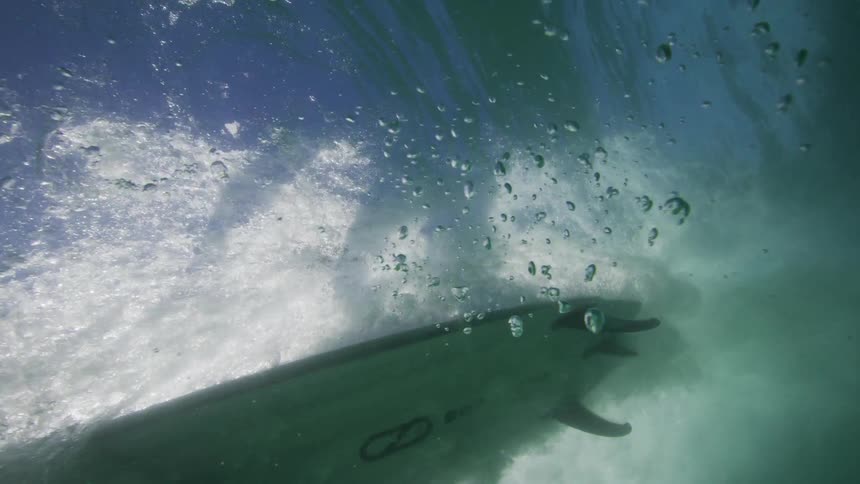 Underwater footage of a surfer riding an ocean wave