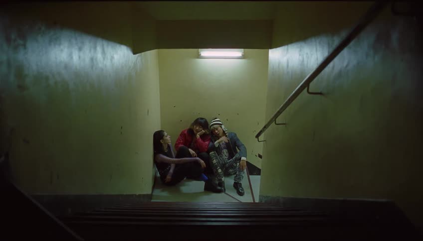 Three people sitting at the base of a staircase
