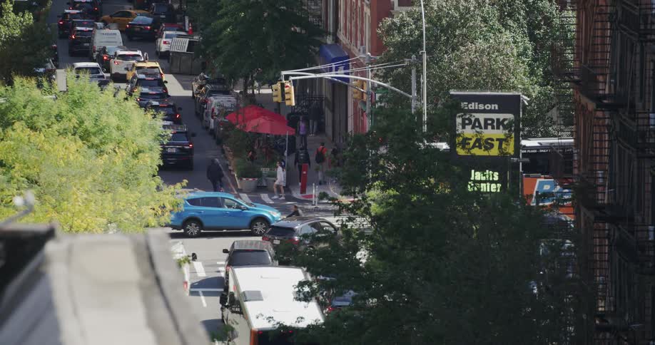 Vehicles merge at an intersection in an urban downtown area on a summer day
