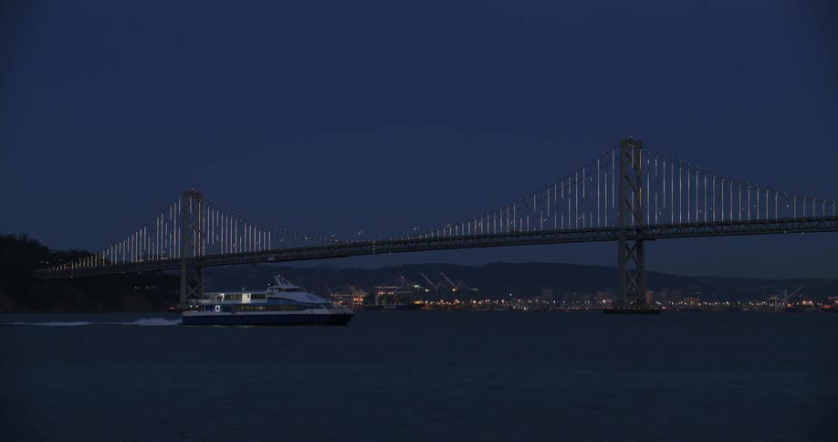 Boat passing through the sea next to a bridge at night