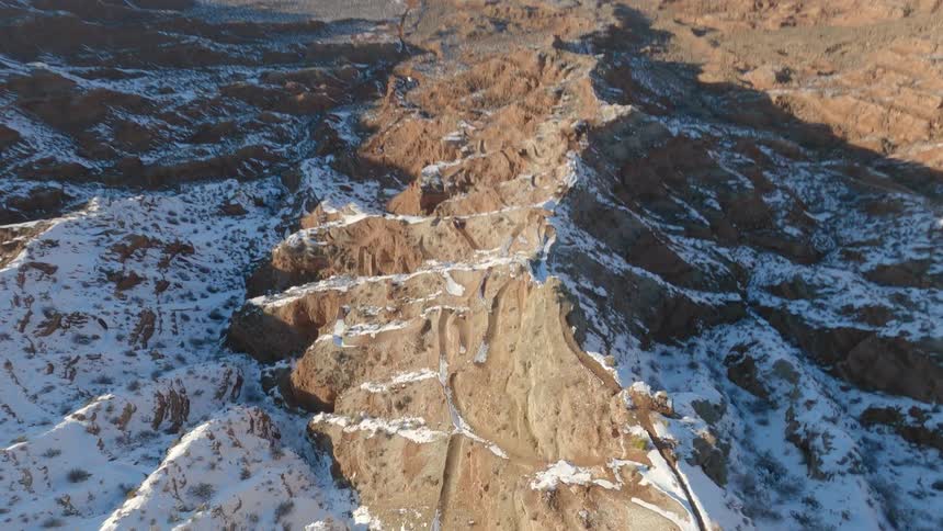 An aerial view of a drone going from the highest point of a rock mountain to the base