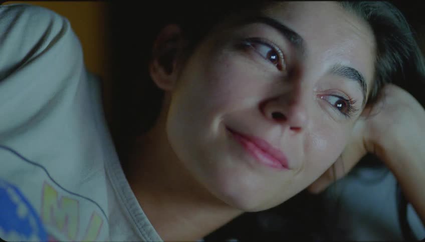 Portrait of a young woman with her hand on her head feeling happy while watching something at night