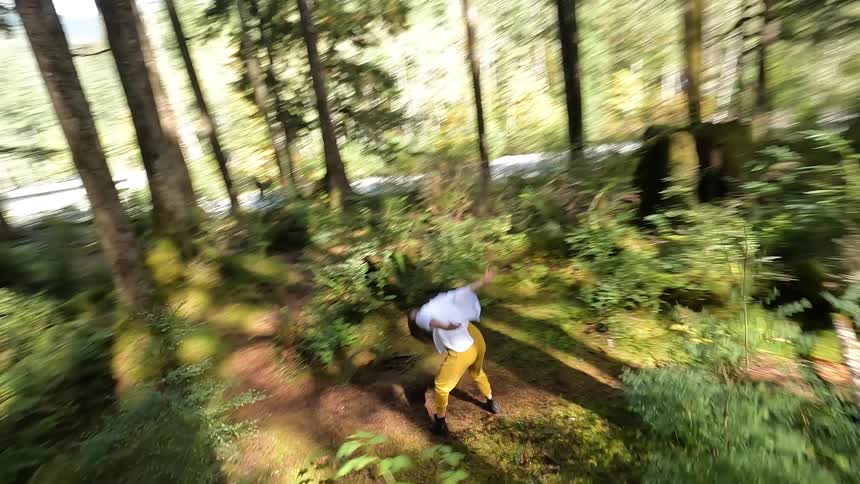 A woman is dancing among trees in the woods