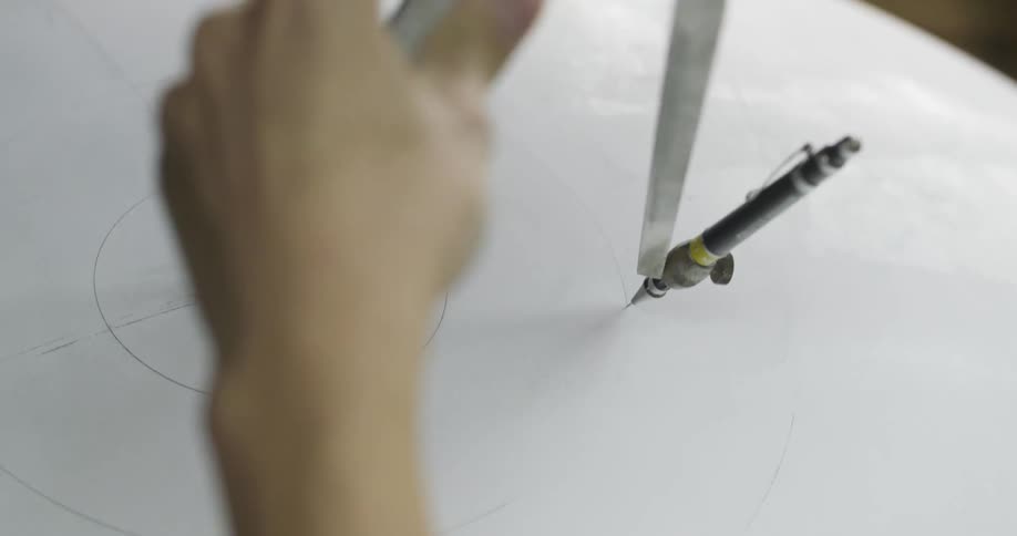 Hand guiding a pencil on a compass around a point on a piece of paper
