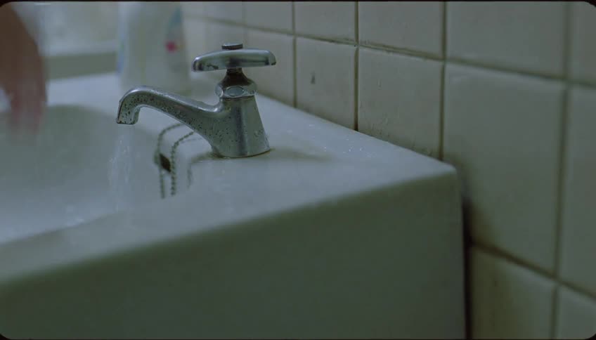 Closeup of a hand opening a sink faucet
