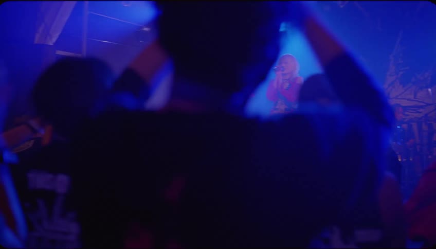 Audience claps while female singer performs on stage in a smoky club