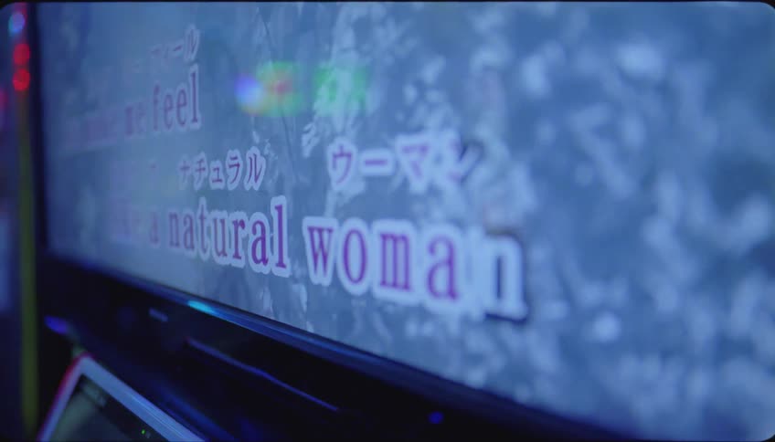 Woman singing at karaoke in an indoor setting with her friends sitting and enjoying