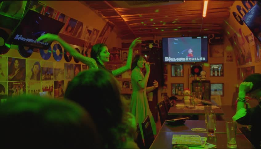 Friends in a pub with one of them singing karaoke and everyone very happy