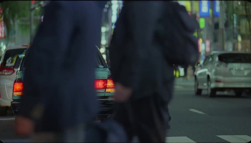 Lady alights from a parked car and walked across the road of a city at night
