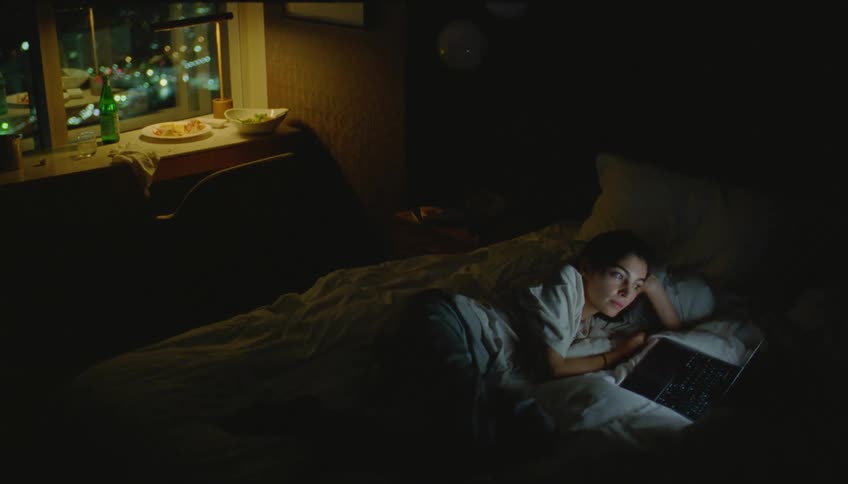 Woman in bed watching a movie on her laptop at night
