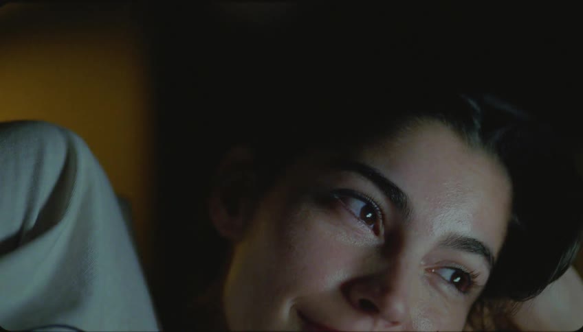 Close up of womans face watching television lying down and laughing