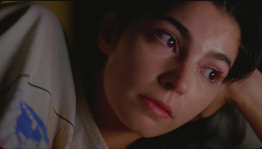 Woman with her head resting on her hand watching something on a screen