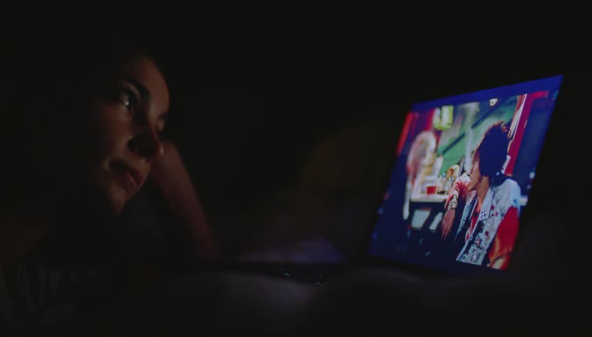 A closeup of a woman watching a movie on a laptop