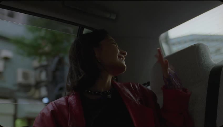A woman waves from the backseat of the car before leaving