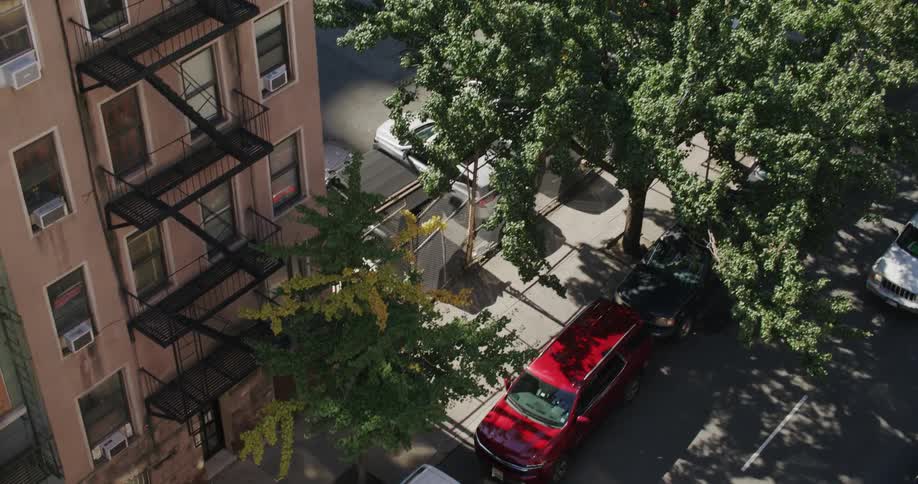 Top view of a street amid residential buildings in a city with parked vehicles and others moving