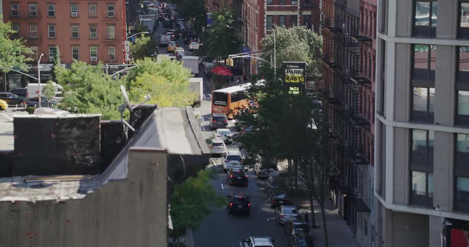 Bustling street in new york city with numerous cars on the road and pedestrians walking on a sunny day