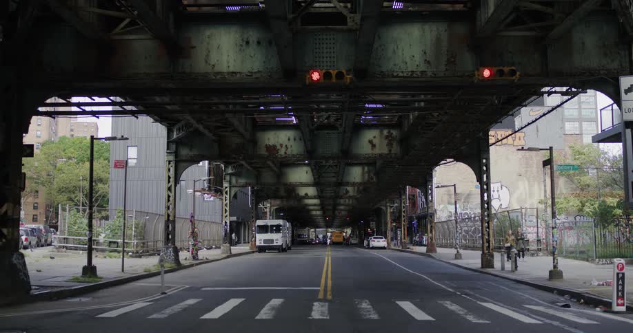 Vehicles cross intersection under elevated roadway in downtown